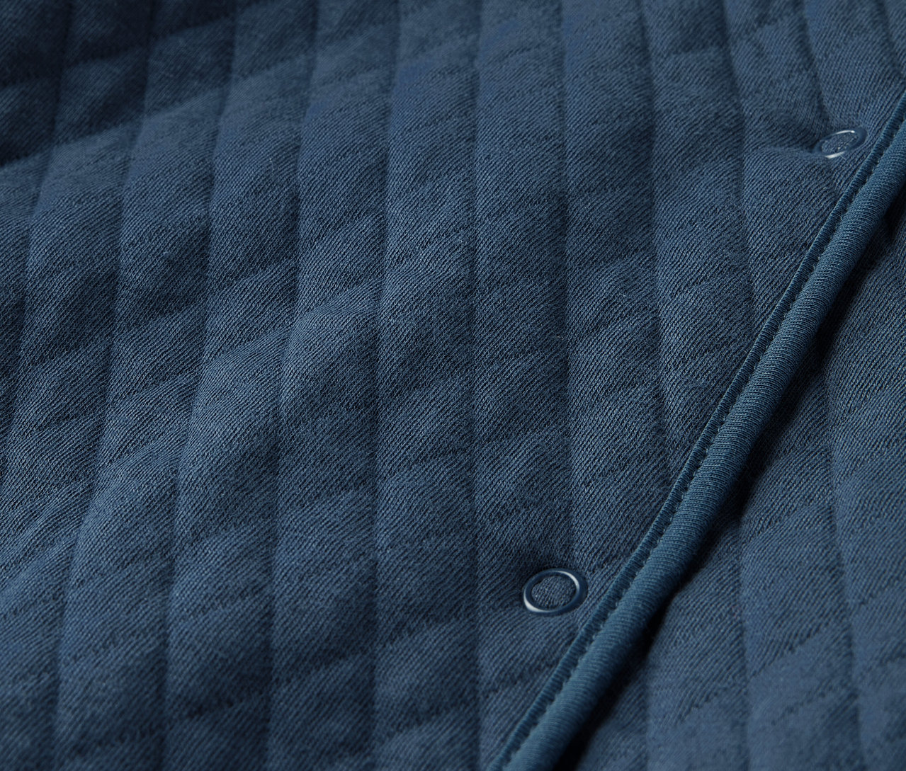 Detailaufnahme eines gesteppten Baby-Jersey-Overalls in Blau.