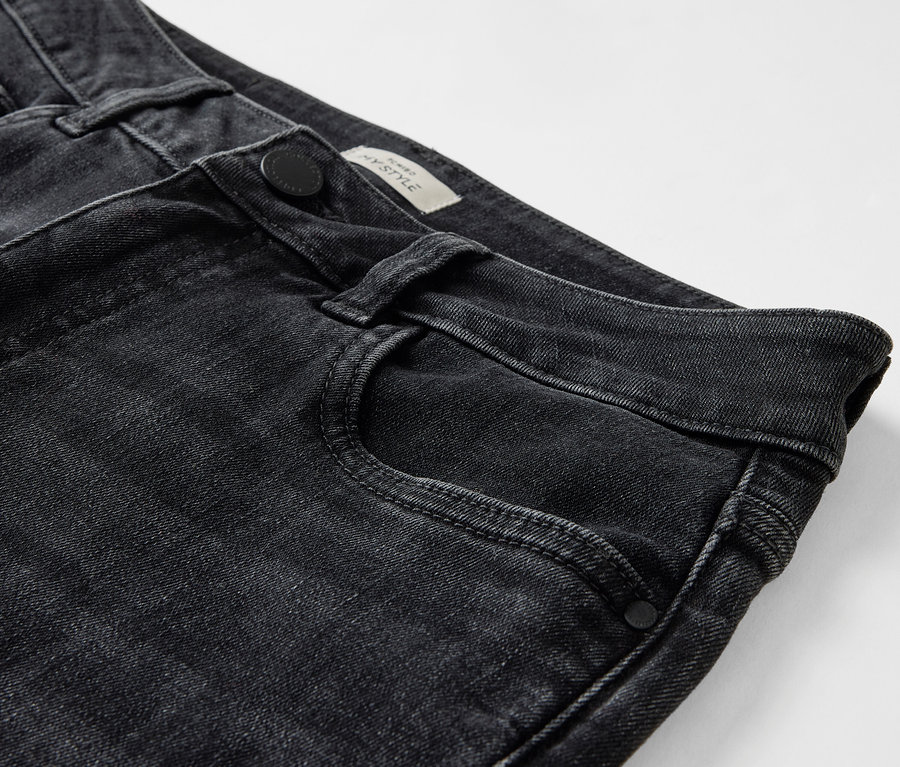 Detailaufnahme einer schwarzen Jeans mit Knopfverschluss und Vordertasche.