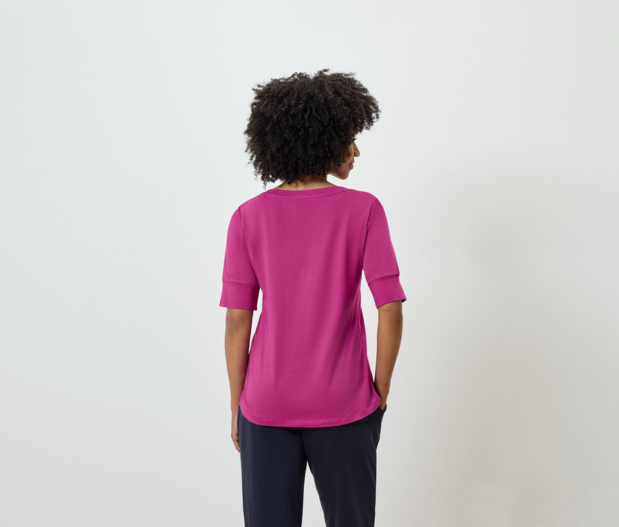 Rückansicht einer Frau mit Afro-Frisur in einem pinkfarbenen T-Shirt und marineblauen Hosen.