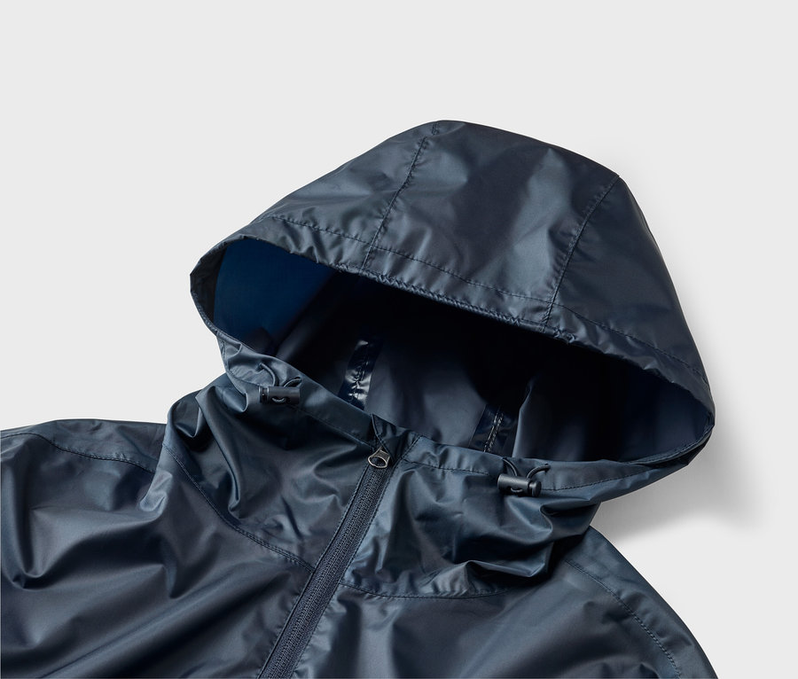 Nahaufnahme einer marineblauen Regenjacke mit Kapuze und Reißverschluss auf hellgrauem Hintergrund.