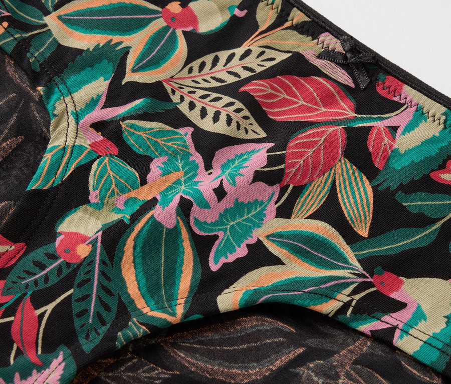 Detailaufnahme einer schwarzen Unterhose mit einem tropischen Blumenmuster.