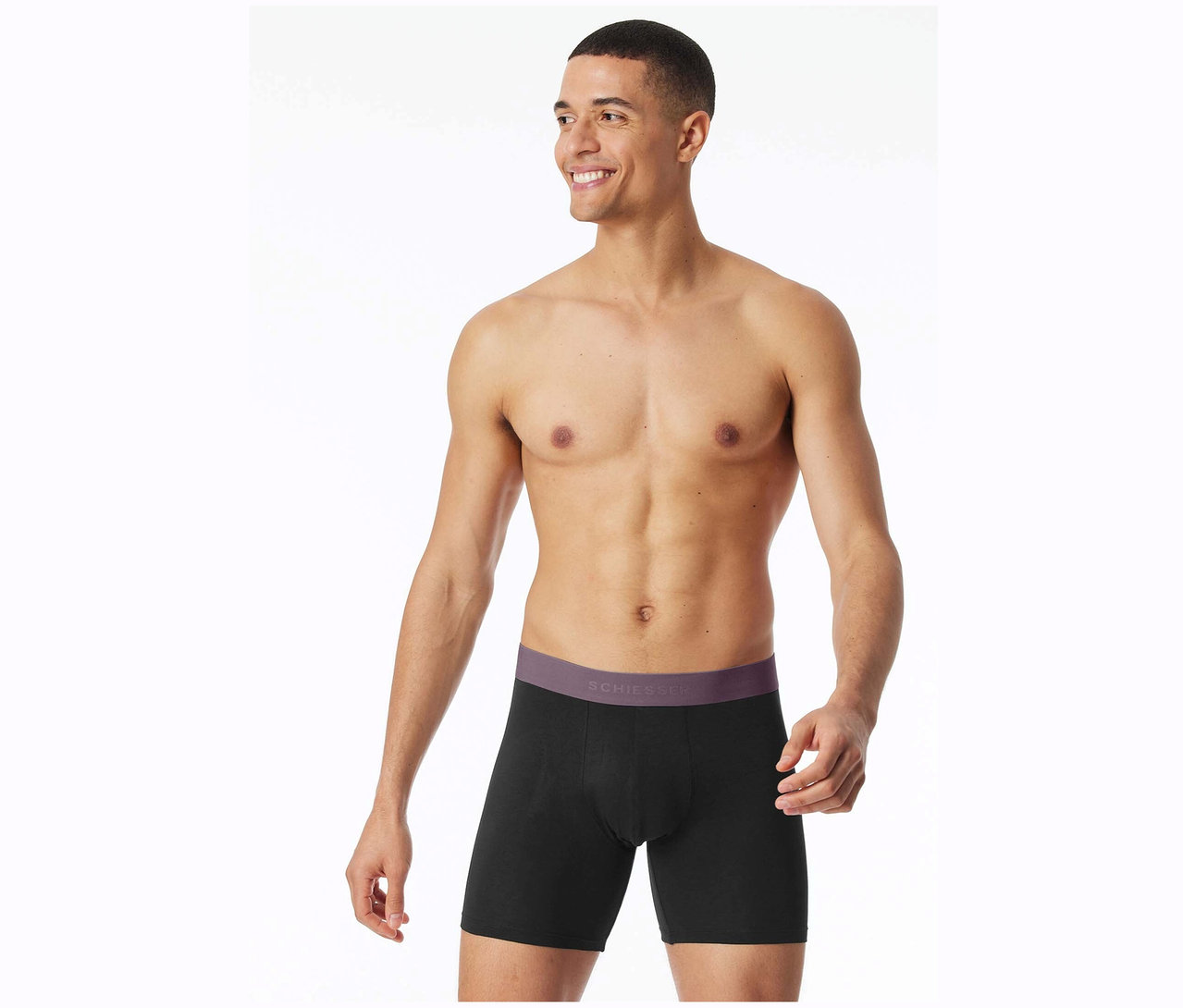 Lächelnder Mann mit freiem Oberkörper posiert in schwarzen Schiesser Boxershorts.