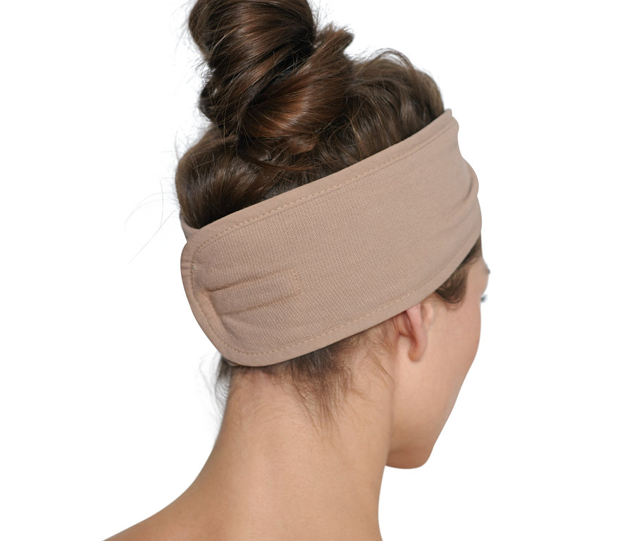 Frau mit hochgesteckten braunen Haaren trägt ein beiges Kosmetik-Stirnband.