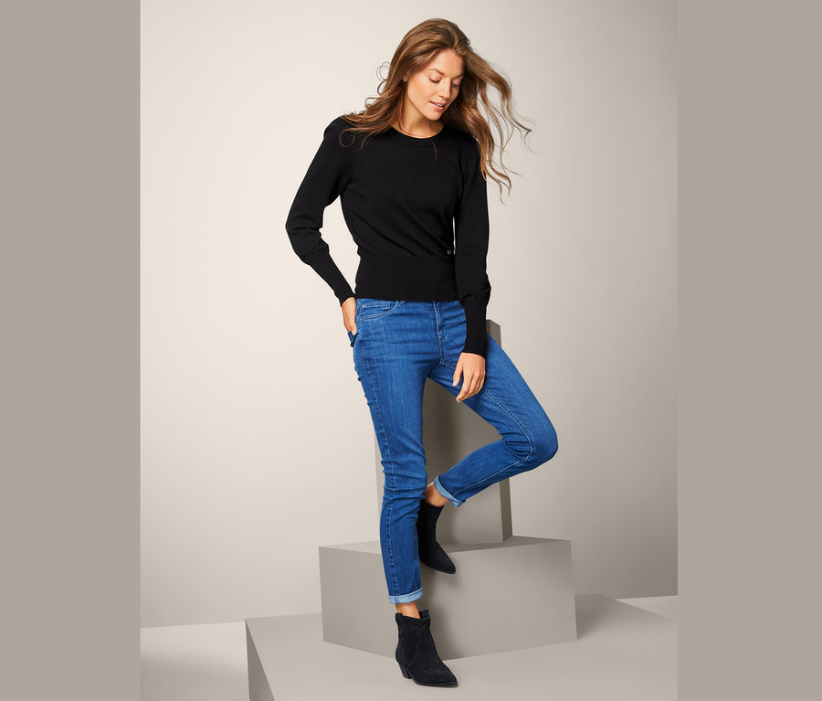 Frau posiert in Feinstrickpullover und blauen Jeans.