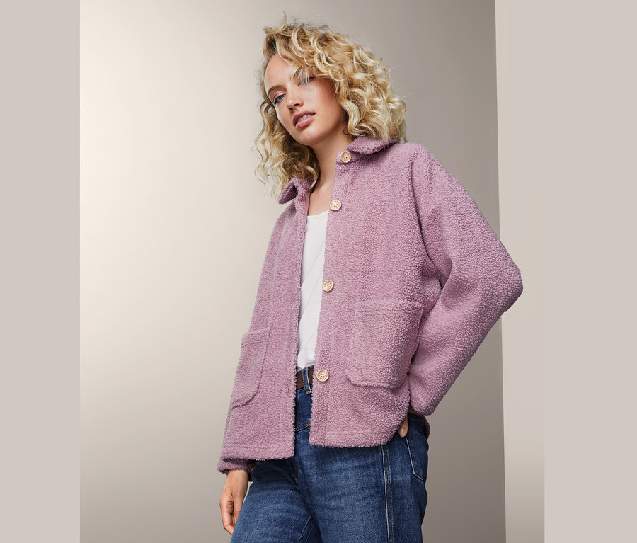 Frau trägt Teddyjacke, Jeans und weißes T-Shirt.