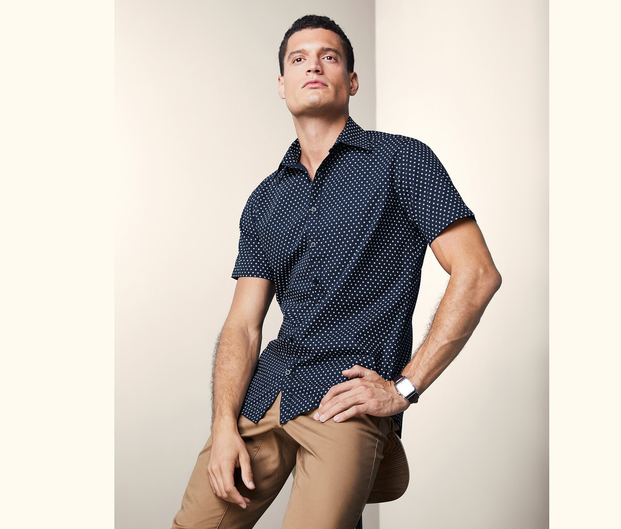 Mann sitzt auf einem Stuhl und trägt ein Kurzarmhemd.