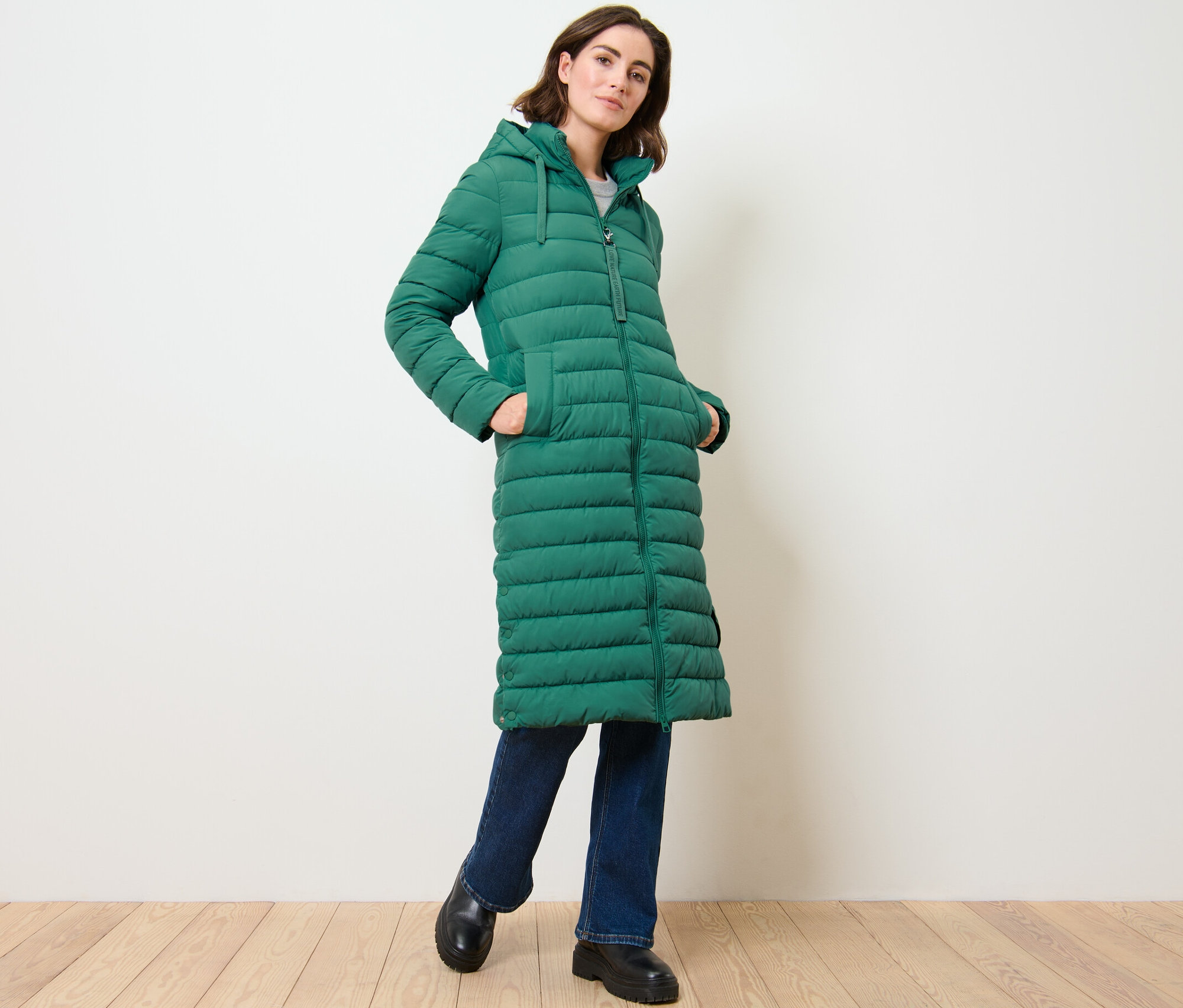 Frau posiert in langem Steppmantel mit Kapuze.