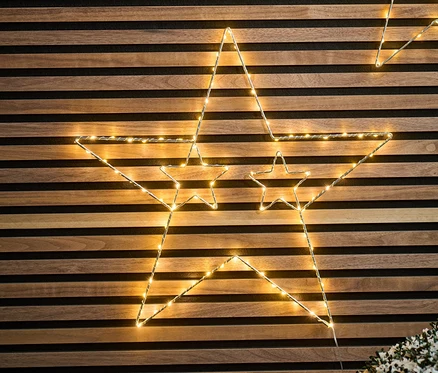 Zwei große, hängende LED-Metallsterne vor einem Holzhintergrund.