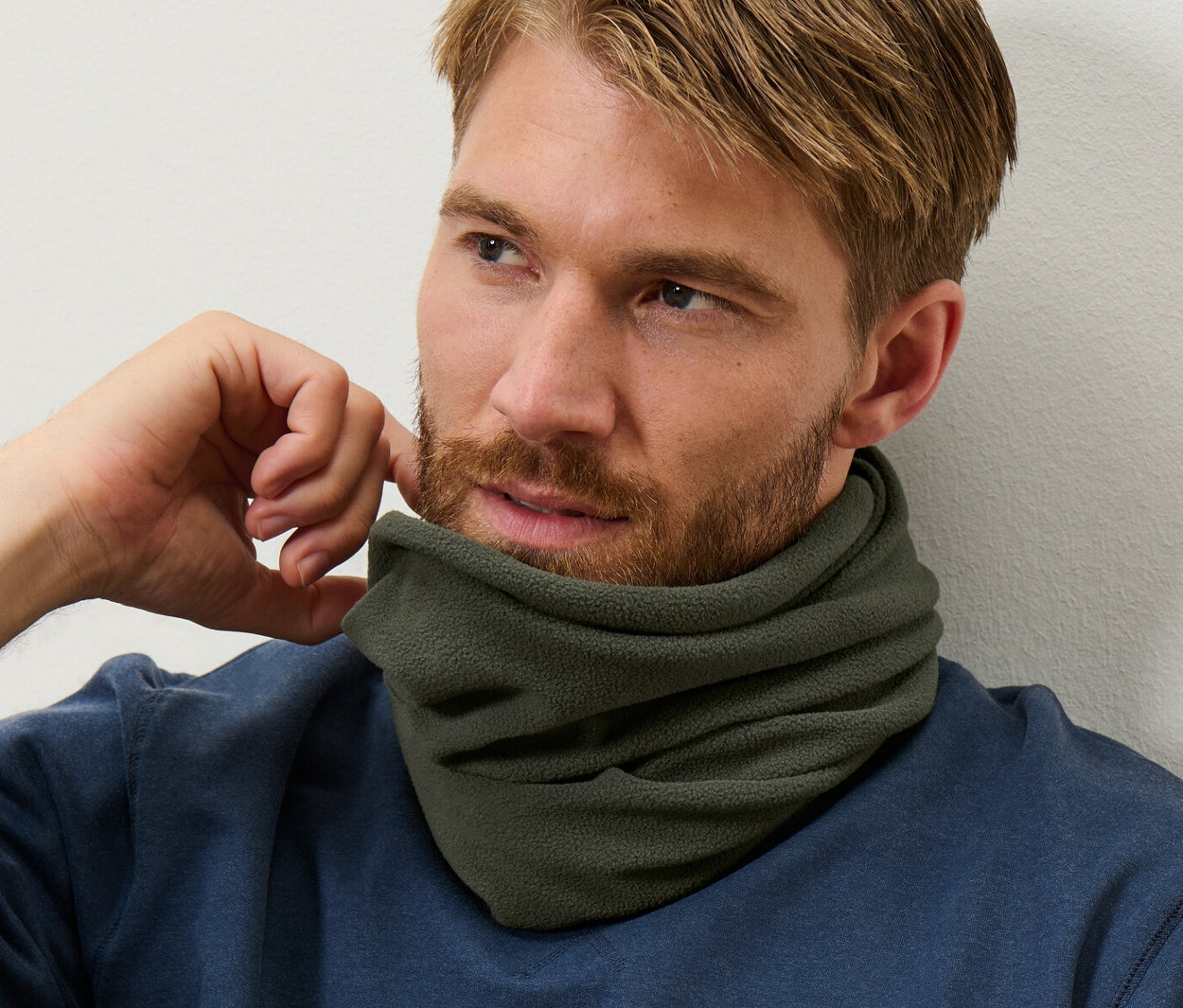 Mann mit braunem Haar und Bart trägt einen blauen Pullover und einen Thermo-Fleecekragen.