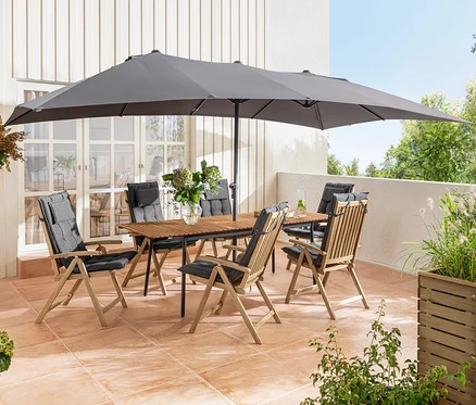 Terrasse mit Ausziehtisch »Elin« und Holz-Hochlehner »Lenja« mit Sun Garden Auflagen unter einem großen, anthrazitfarbenen Leco Doppel-Sonnenschirm.