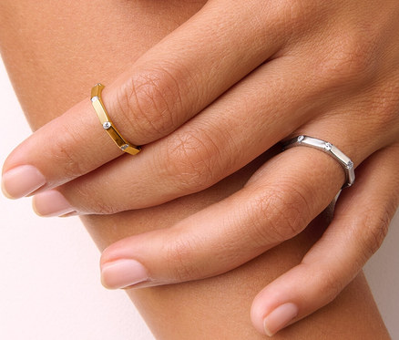 Detailaufnahme einer Damenhand, die einen goldenen 925 Silber Ring Octagon und einen 925 Silber Ring Octagon trägt.