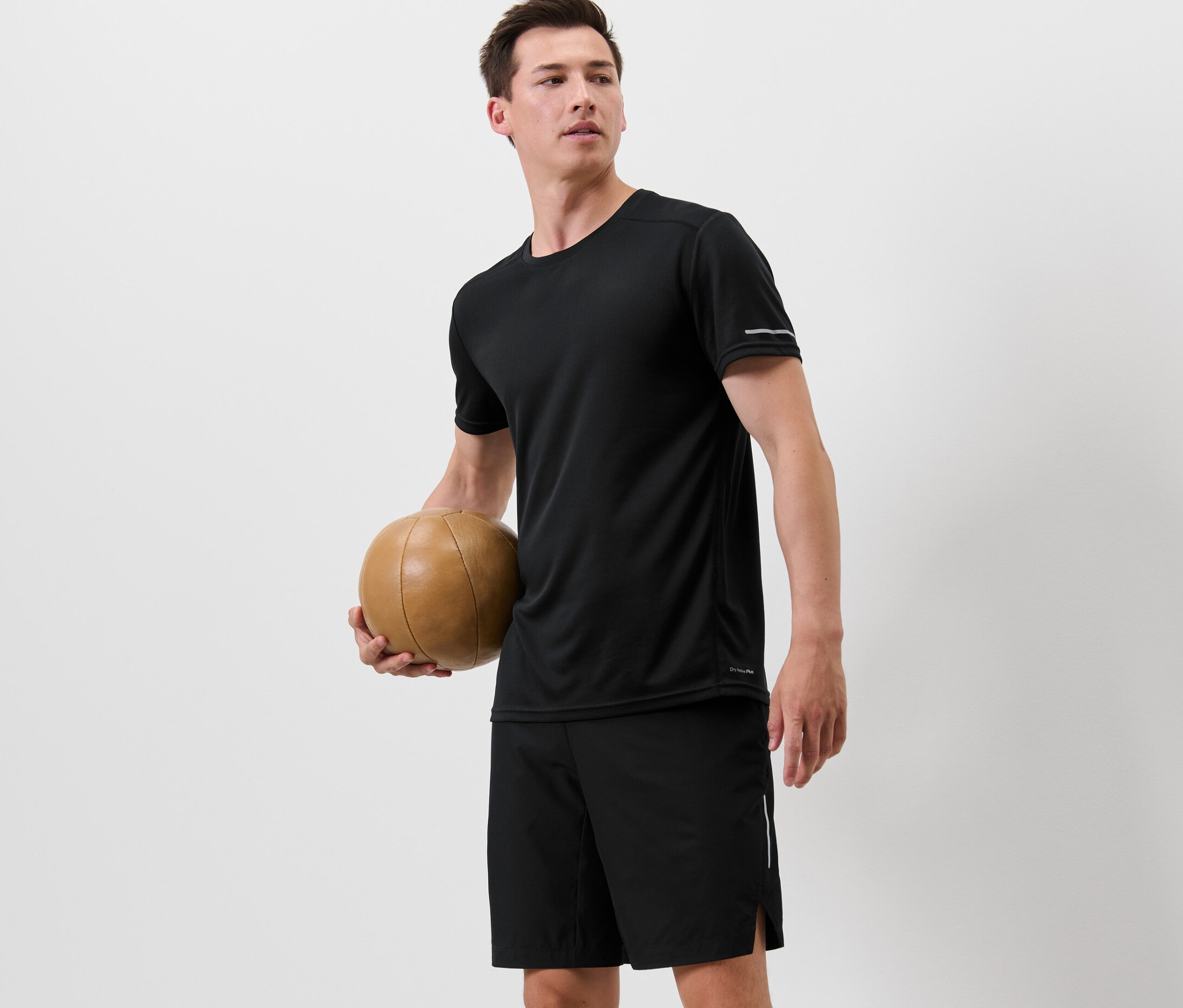 Mann hält einen Basketball und trägt ein schwarzes Funktionsshirt.