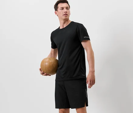 Mann hält einen Basketball und trägt ein schwarzes Funktionsshirt.