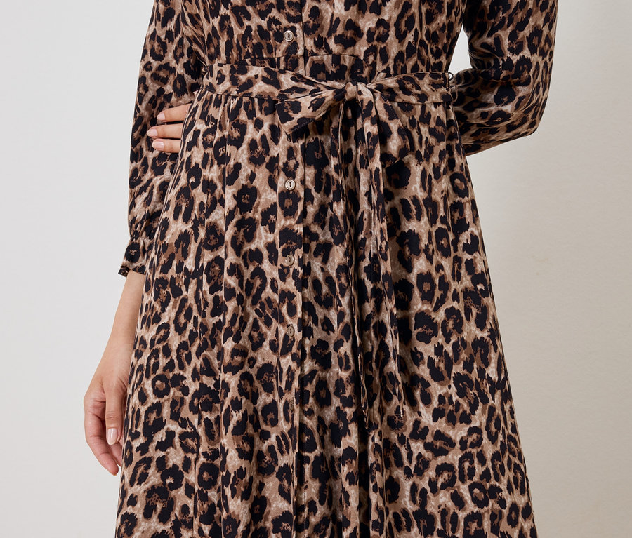 Teilansicht einer Frau in einem braunen Kleid mit Tiermuster und Gürtel.