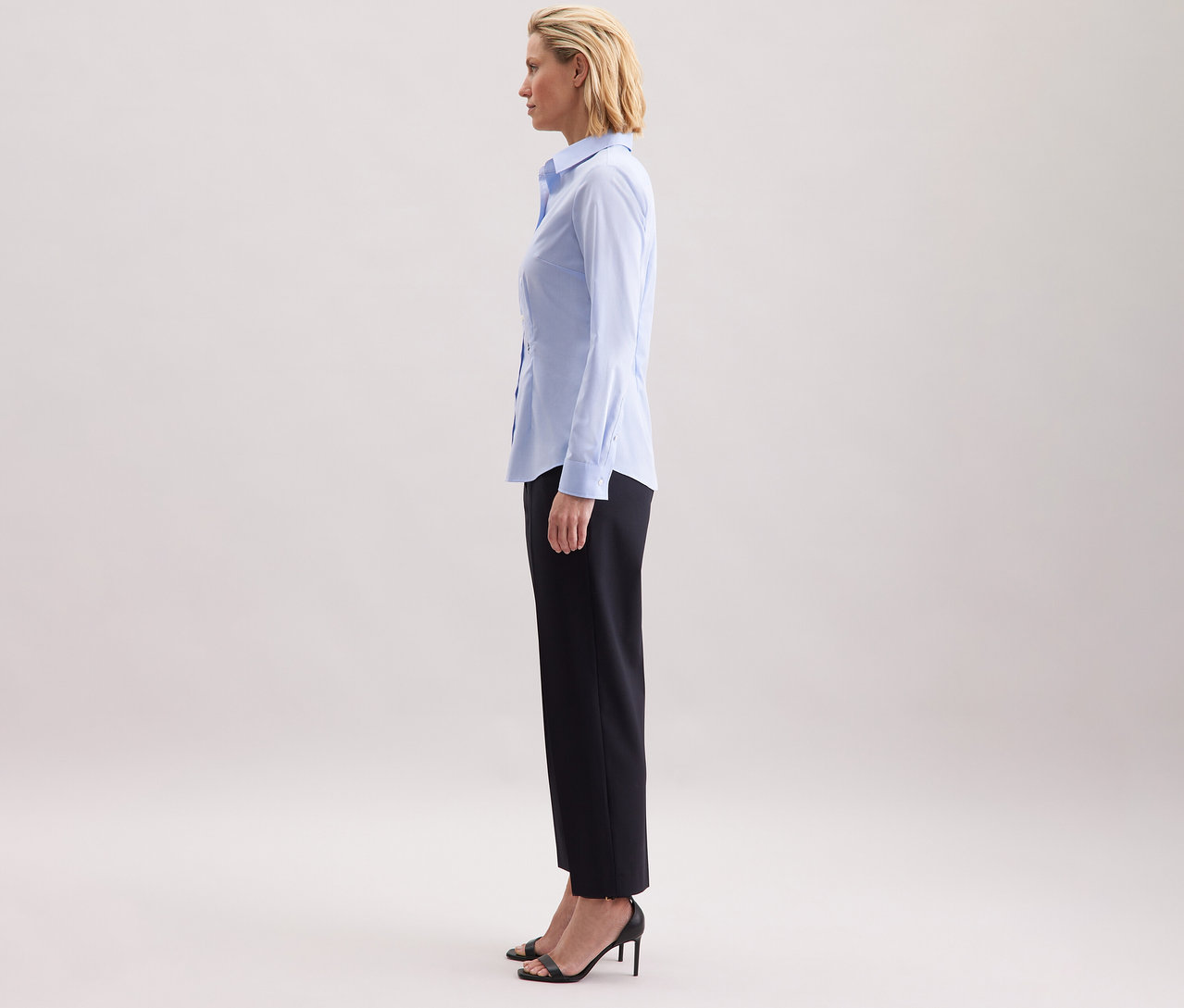 Frau steht seitlich und trägt eine hellblaue Seidensticker Bluse Slim Fit non iron.