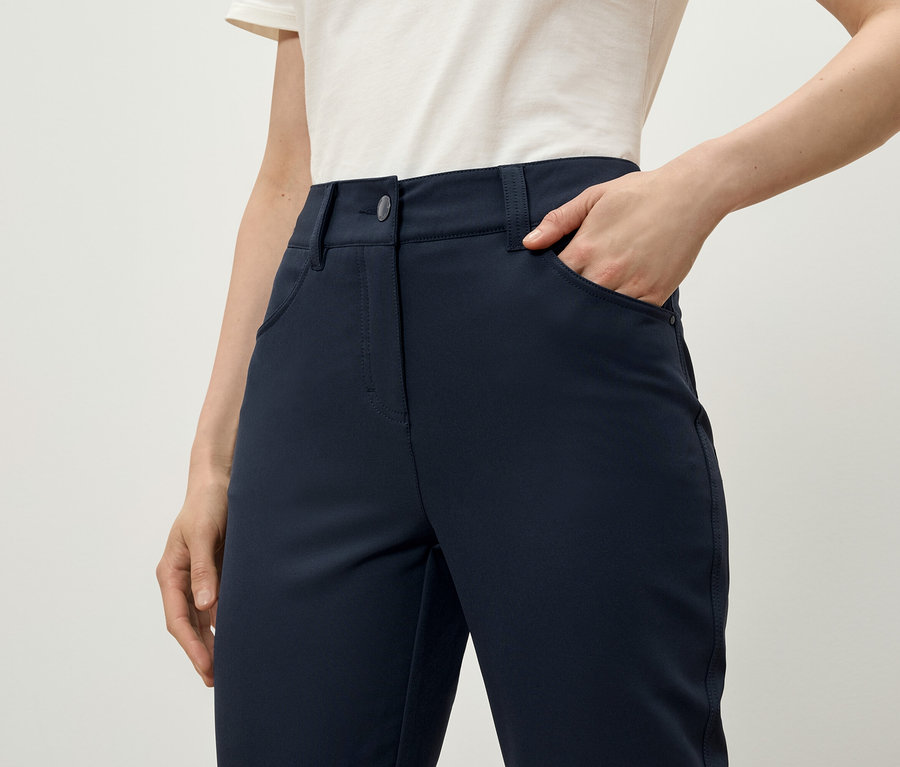 Frau hat Hand in der Tasche einer dunkelblauen Hose.