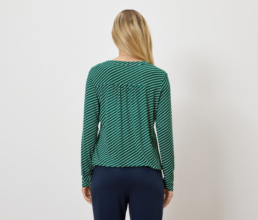 Frau trägt ein grün gestreiftes Langarmshirt und dunkelblaue Hosen.
