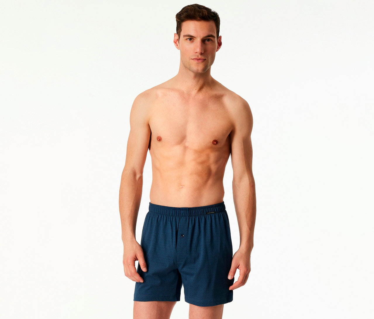 Mann mit freiem Oberkörper trägt blaue 2 SCHIESSER Boxershorts vor einem weißen Hintergrund.