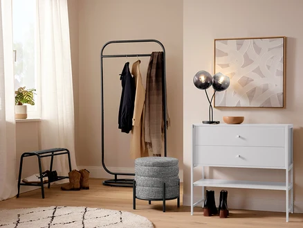 Flur mit einer Tischleuchte mit Schirmen aus Rauchglas, einem Indoorteppich »NOMAD Rhombus Line« und einer Garderobe.