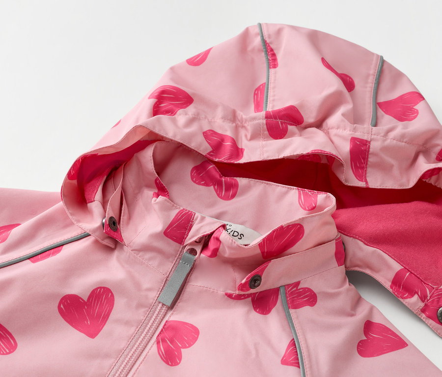 Nahaufnahme einer hellrosa Kinderjacke mit Kapuze und einem Muster aus dunkelrosa Herzen.