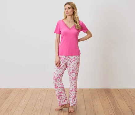 Frau in einem pinken T-Shirt mit Spitzendetails und einer geblümten Pyjamahose.