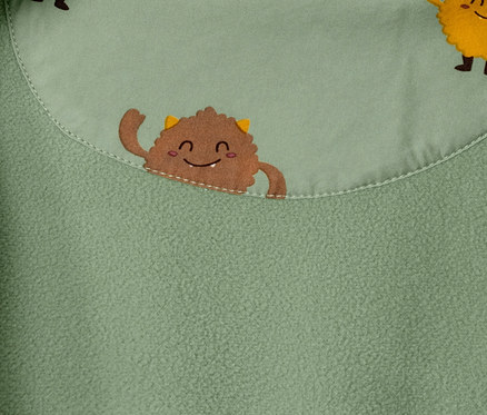 Detailaufnahme eines grünen Softshell-Einteilers mit Monsterprint.