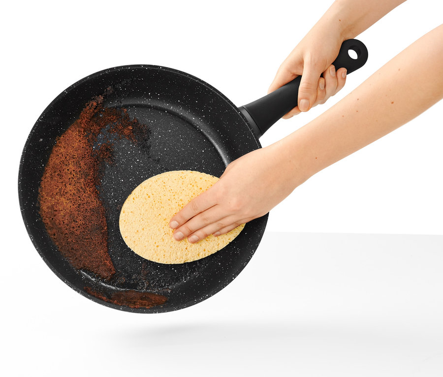 Eine 28 cm große Profi-Pfanne in Steinoptik wird mit einem Schwamm gereinigt.