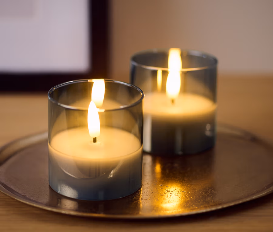 Zwei kleine LED-Echtwachskerzen im Glas auf einem goldenen Tablett.