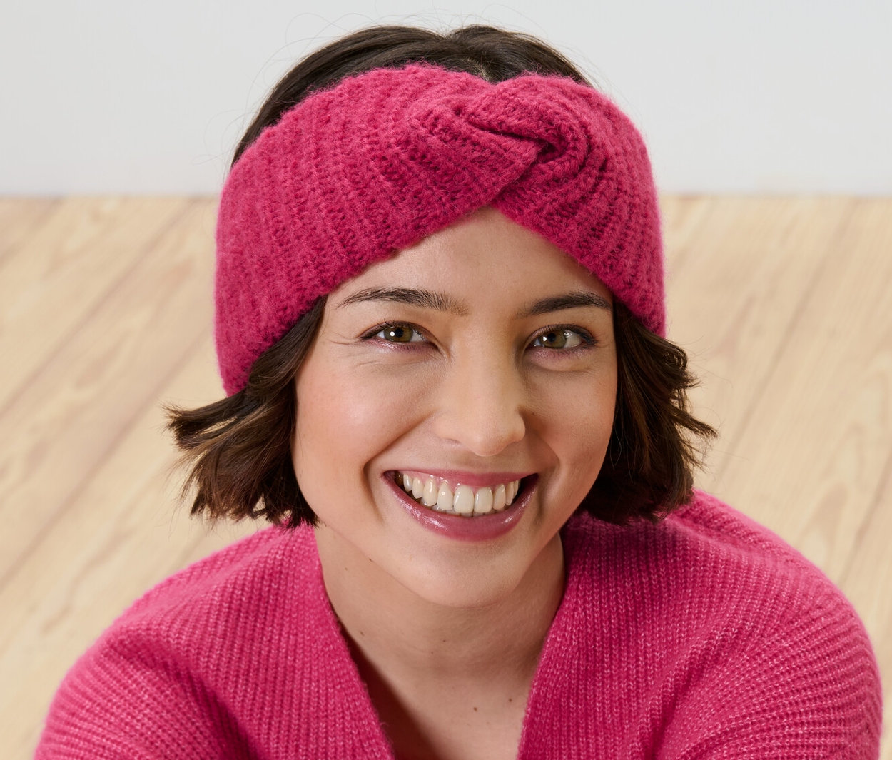 Frau lächelt und trägt ein rosa Stirnband.