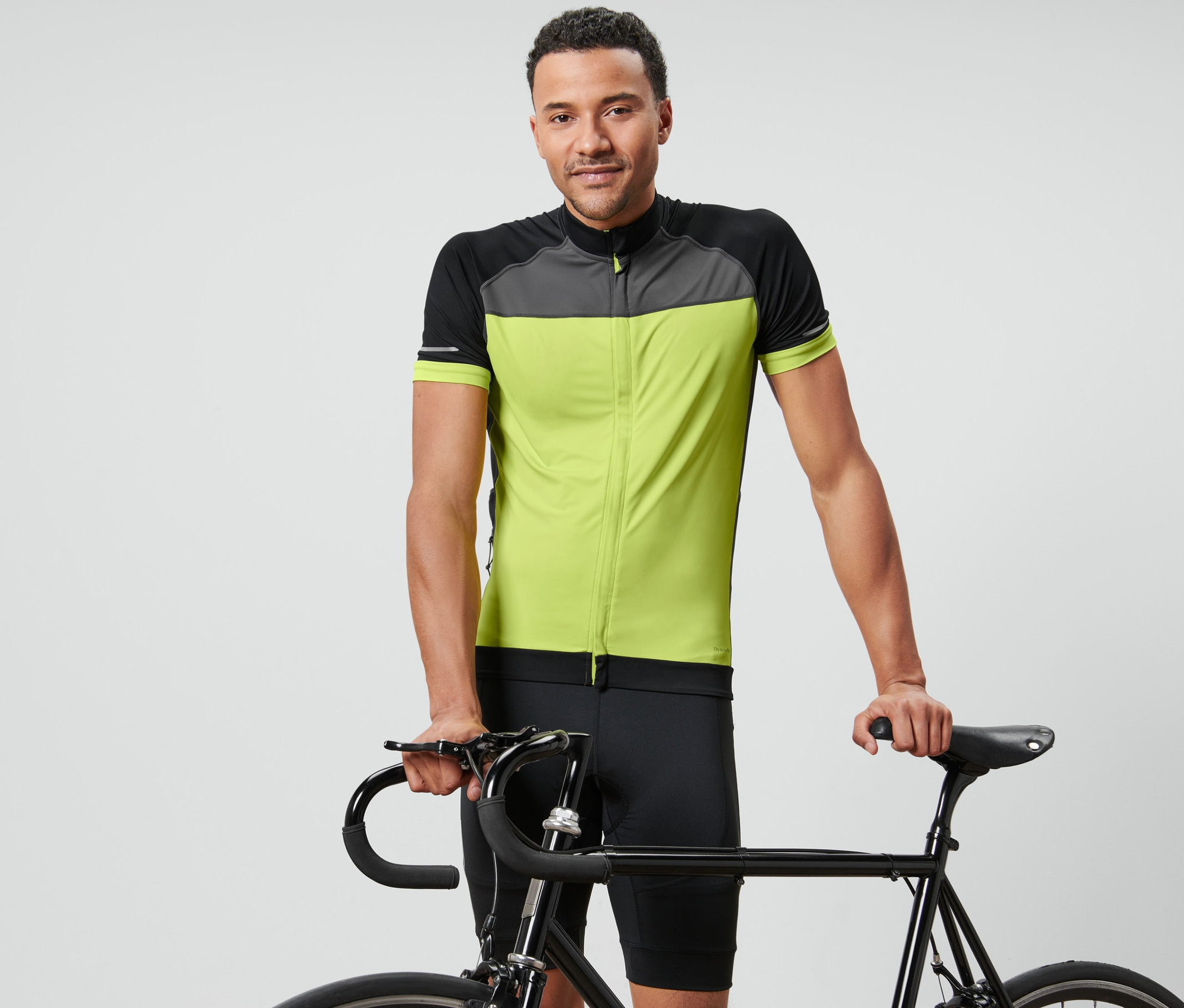 Ein Mann posiert mit einem Fahrrad und trägt ein Fahrrad-Trikot.