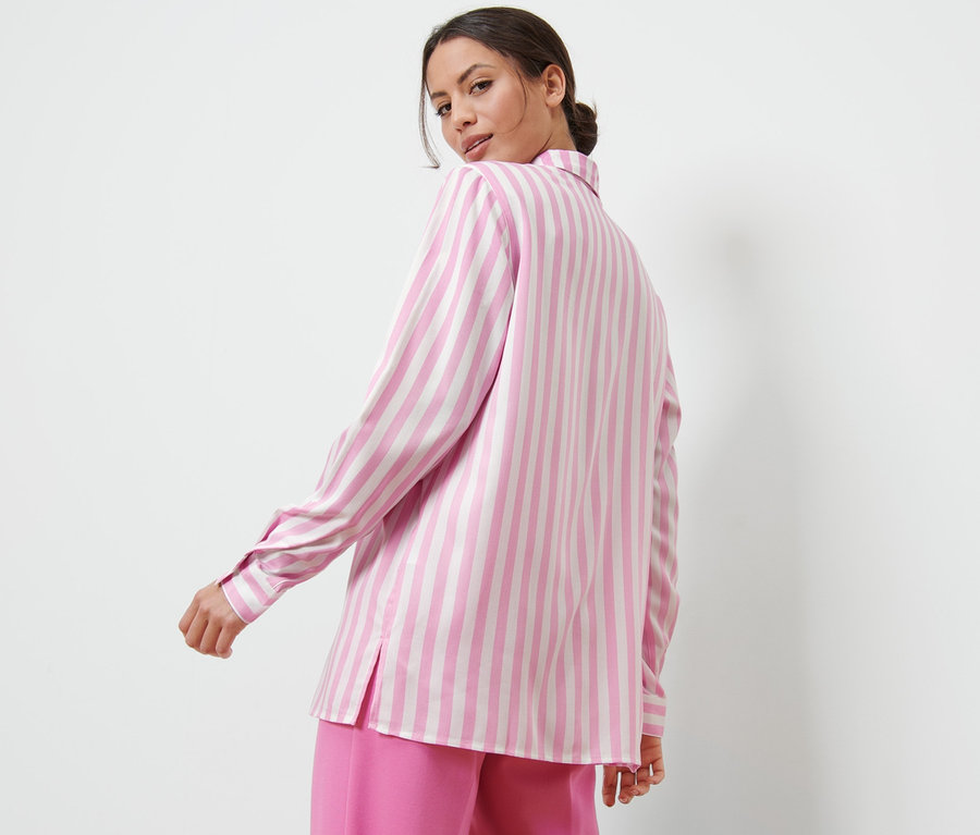 Frau blickt über die Schulter und trägt eine rosa gestreifte Bluse.