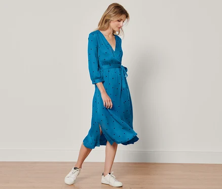 Frau steht und trägt ein gepunktetes Webkleid.