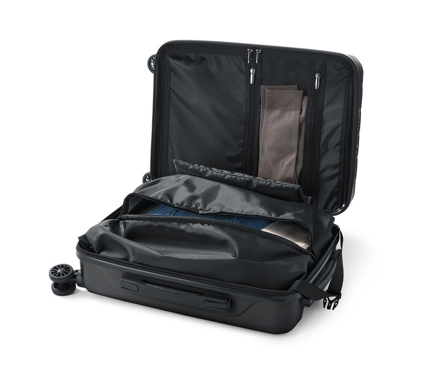 Ein geöffneter, kleiner Hartschalen-Koffer mit teilweise gepackter Kleidung.
