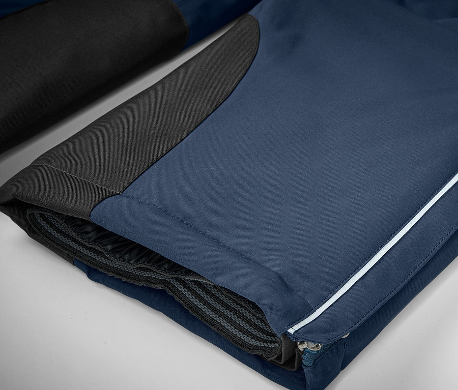 Detail einer blauen Hose mit schwarzen Details und einem weißen Streifen.
