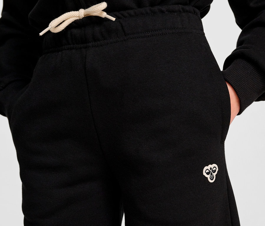 Nahaufnahme einer Person in hummel® HMLJR Loose WL Sweatpants mit Händen in den Taschen.