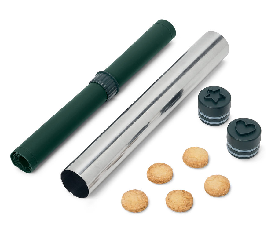 Eine grüne Rollmatte und eine silberne Teigrolle mit stern- und herzförmigen Ausstechern und Keksen.