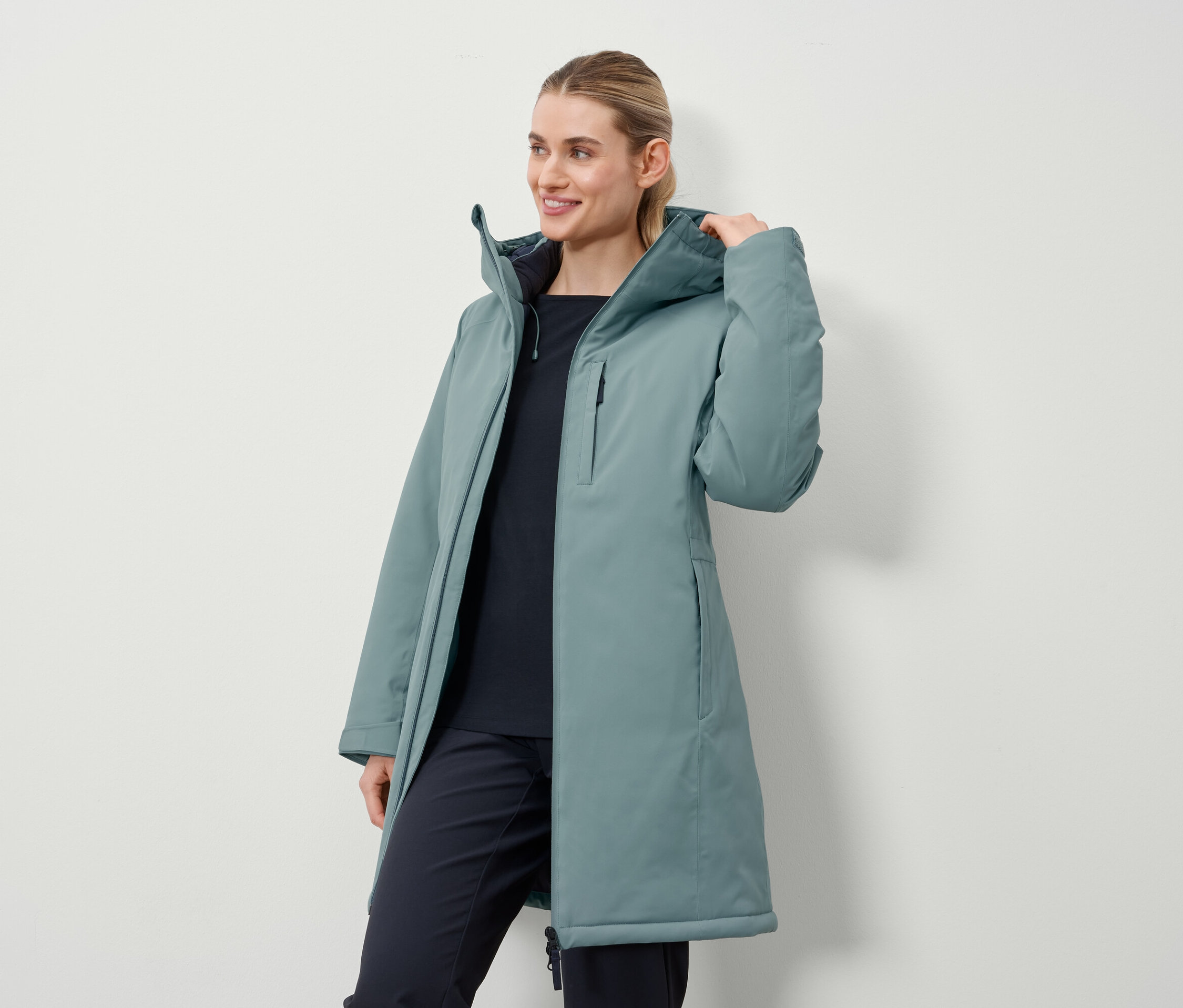 Eine Frau trägt einen petrolfarbenen, langen Mantel.