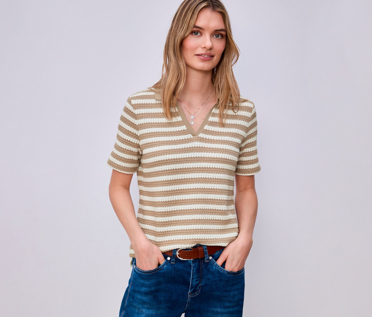 Frau mit Jeans und braunem Gürtel trägt ein gestreiftes Street One Strickshirt mit V-Ausschnitt.