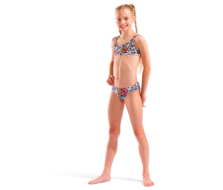 Mädchen mit blonden Zöpfen, das einen weißen Bikini mit buntem Muster trägt und lächelt.