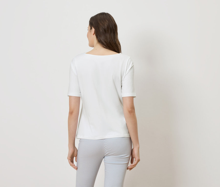 Rückansicht einer Frau mit braunen Haaren, die ein weißes T-Shirt und eine blau-weiß gestreifte Hose trägt.