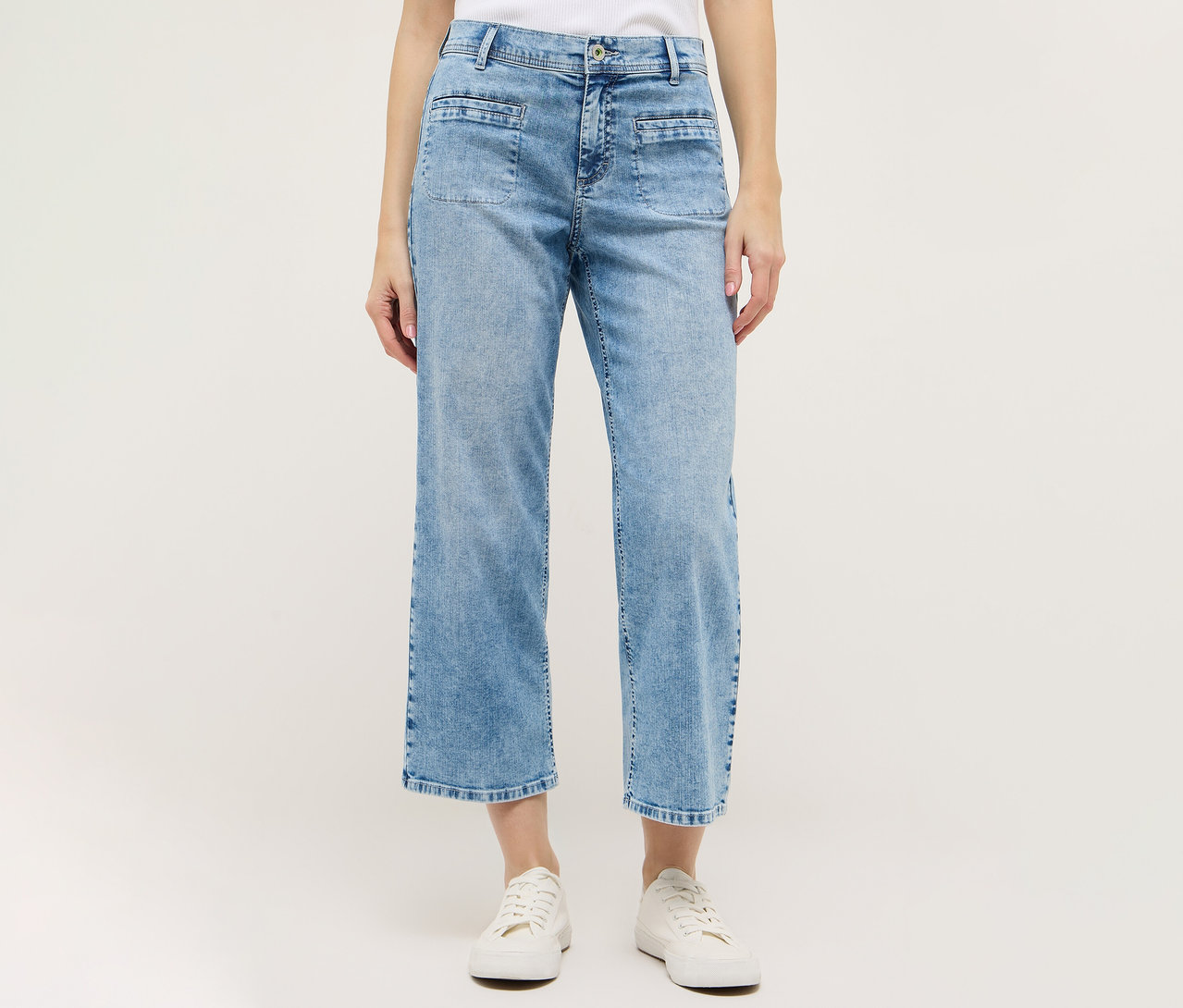 Frau trägt hellblaue Angels Denim »Linn Smart« Culotte und weiße Schuhe vor weißem Hintergrund.