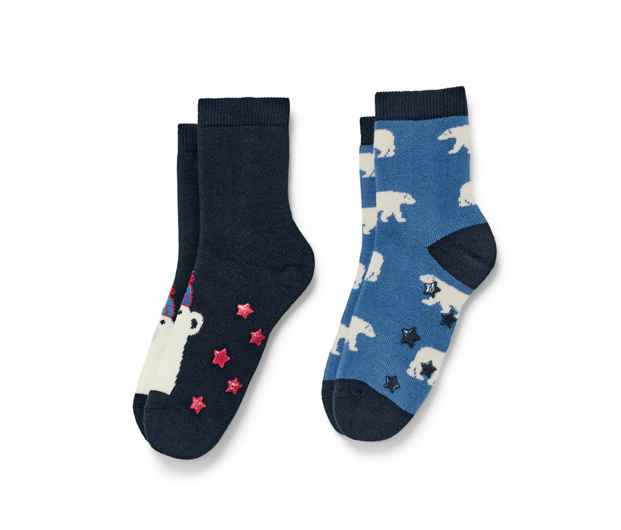 Zwei Paar Socken. Ein Paar ist marineblau mit einem weißen Bären mit Geburtstagshut und roten Sternen, das andere Paar ist blau mit weißen Eisbären und dunklen Sternen.