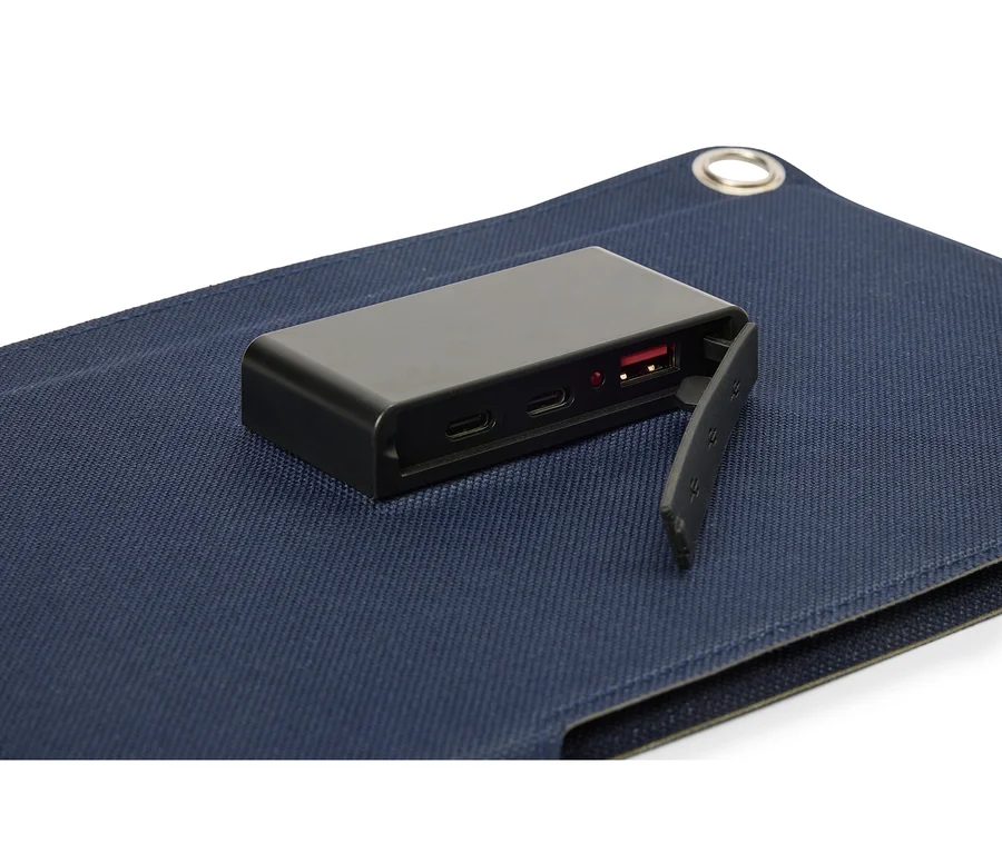 Schwarzer Akku liegt auf einer blauen Stoffoberfläche, wobei der USB-Anschluss sichtbar ist.
