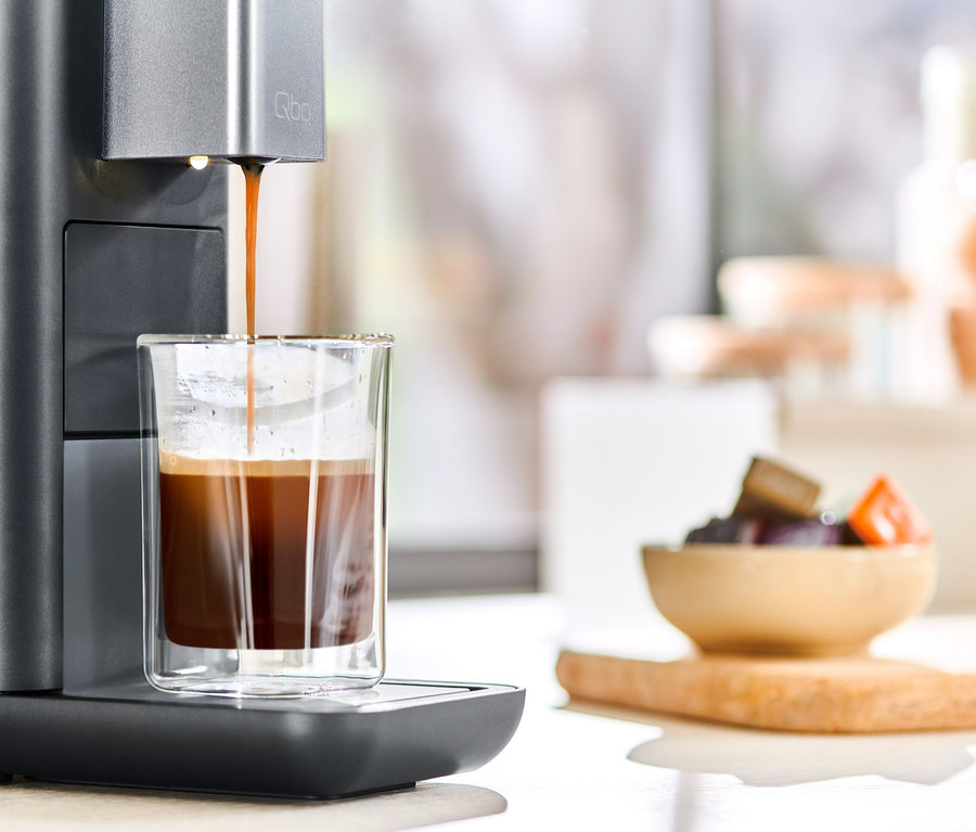 Kaffee läuft aus einer Qbo ESSENTIAL Dark Stone Kaffeemaschine in ein Glas.