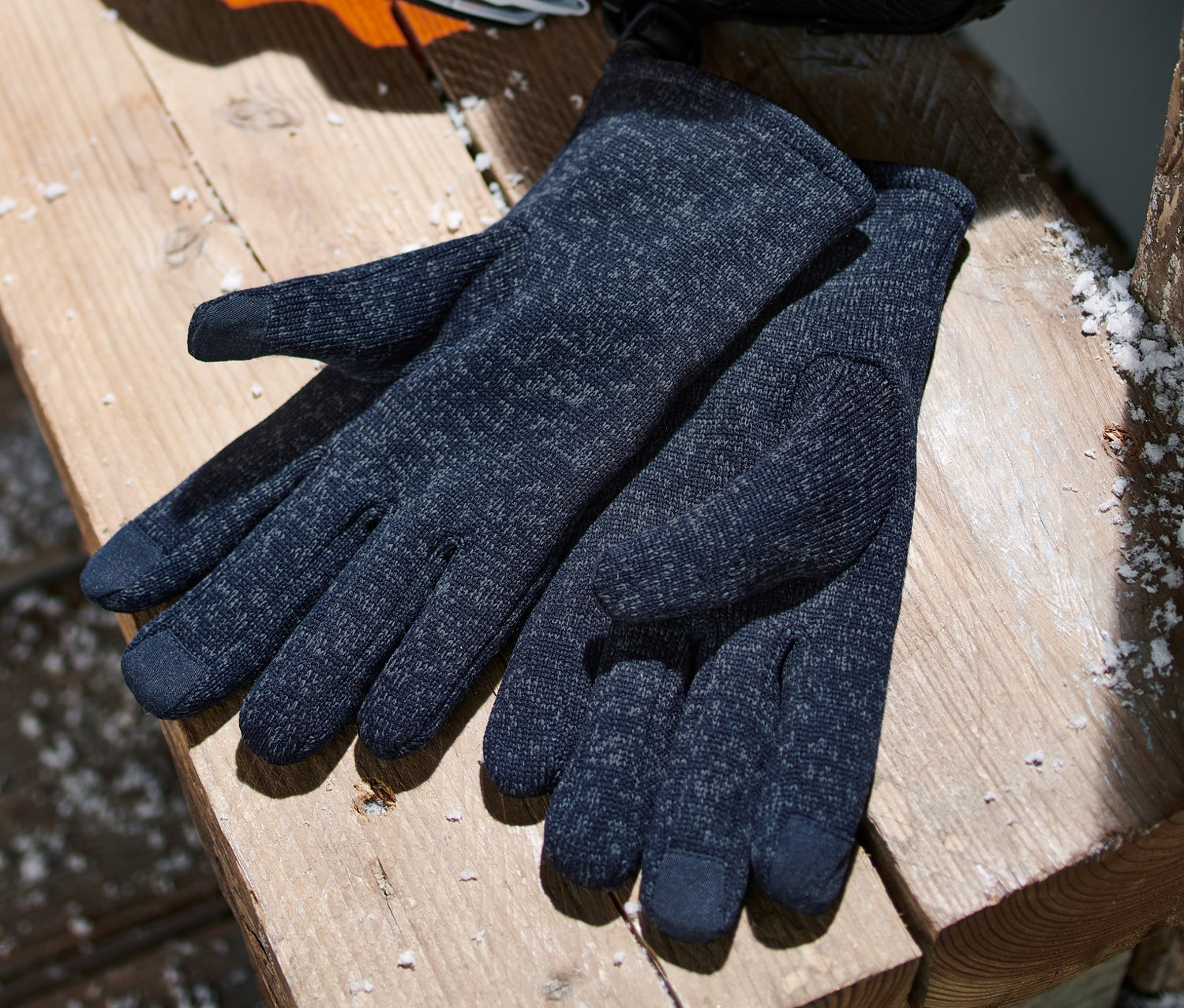 Dunkelblaue Strickfleece-Handschuhe liegen auf einer Holzbank.