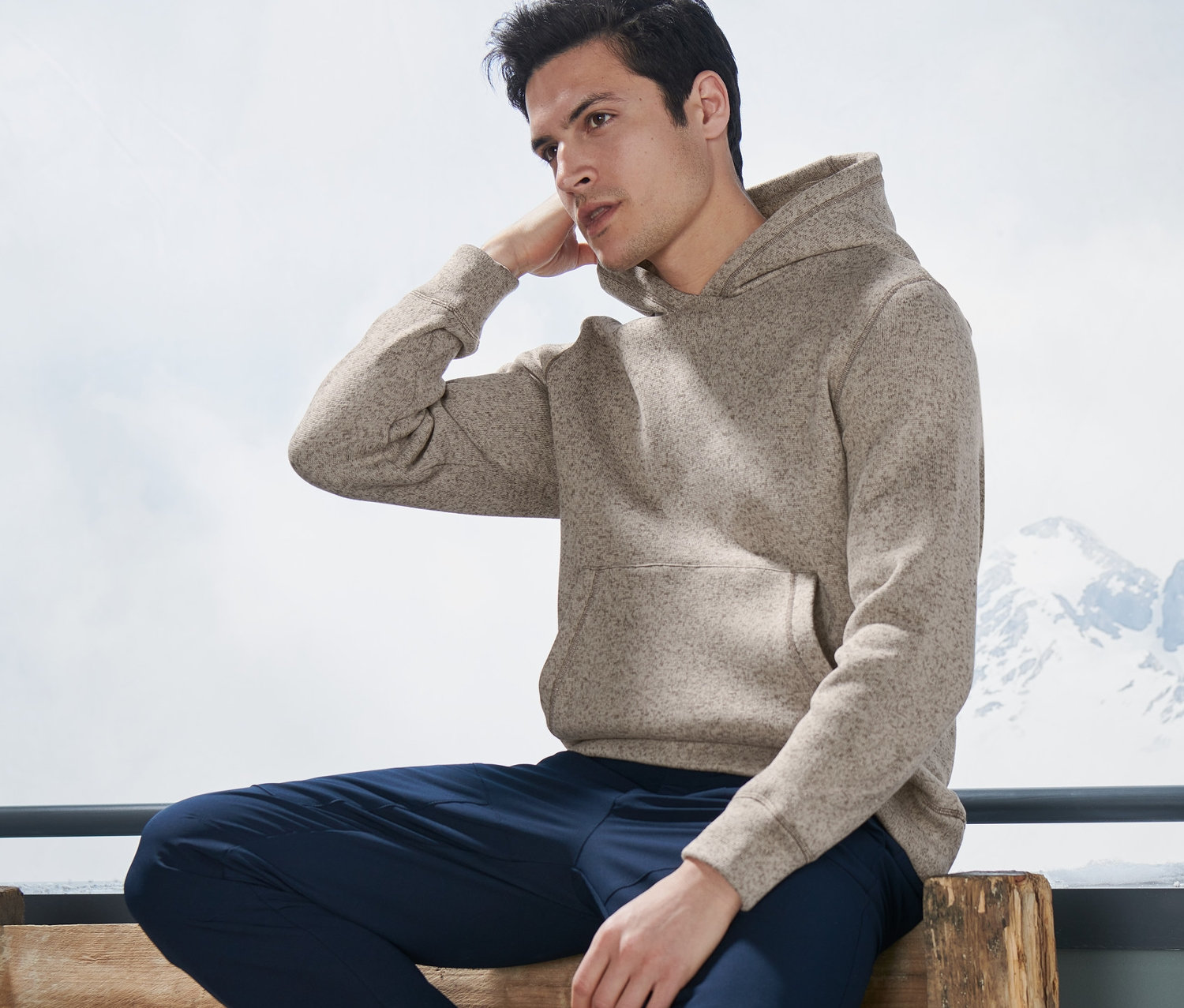 Mann sitzt auf Bank, trägt Strickfleece-Midlayer.