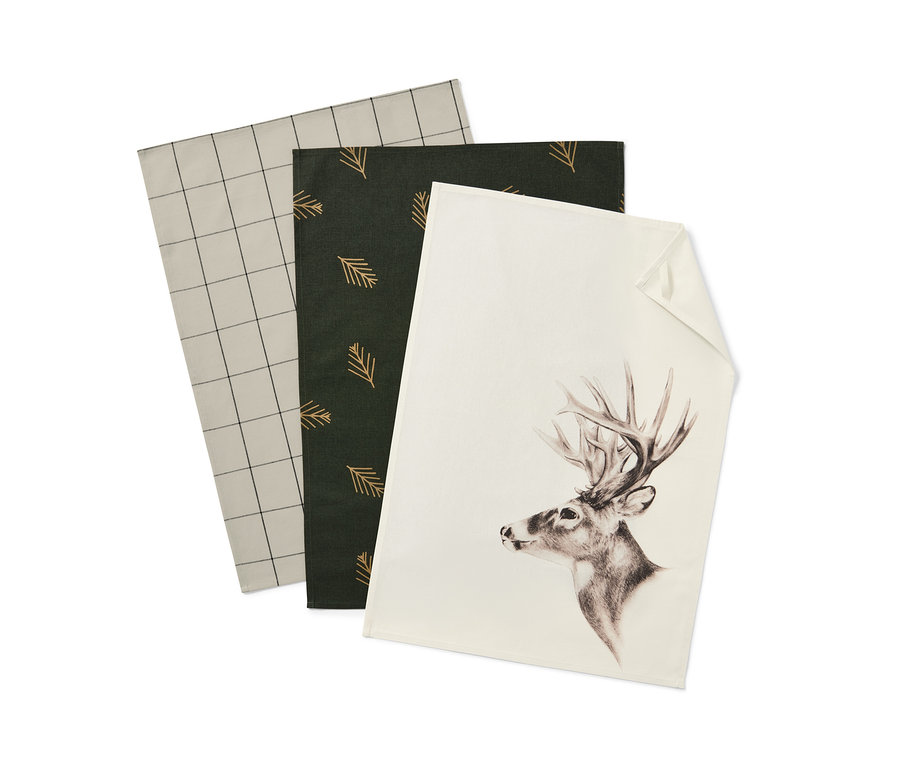 Drei Geschirrtücher: Eines mit grau-weißem Karomuster, eines mit dunkelgrünen Nadelbaum-Motiven und eines mit einem Hirsch.