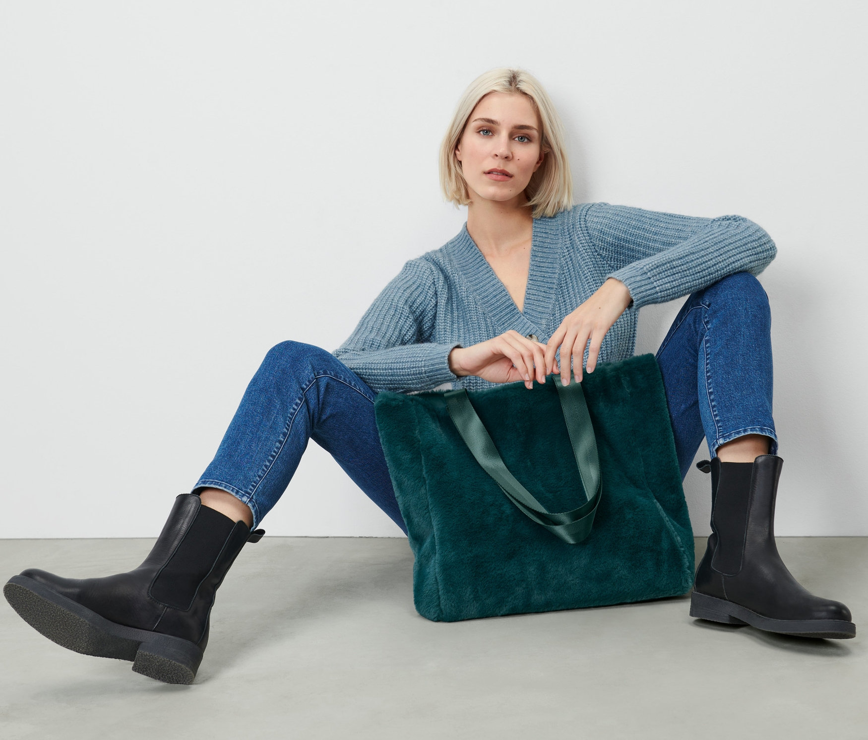 Frau sitzt mit Teddy-Tasche.