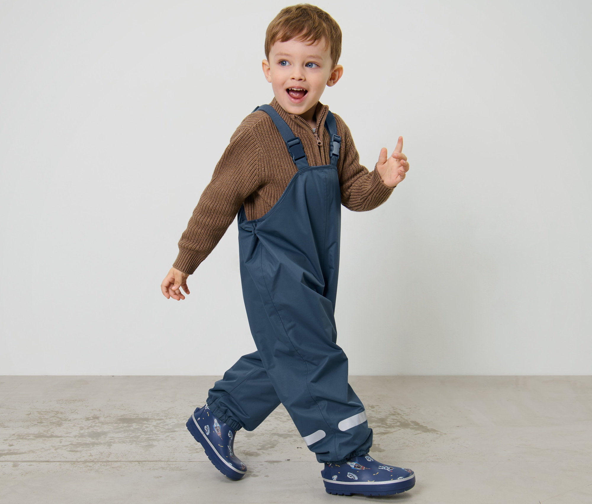 Junge geht, trägt eine dunkelblaue Kinder-Thermo-Regenhose.