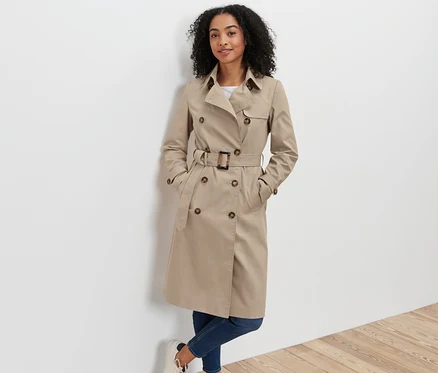 Frau posiert in beige Trenchcoat.